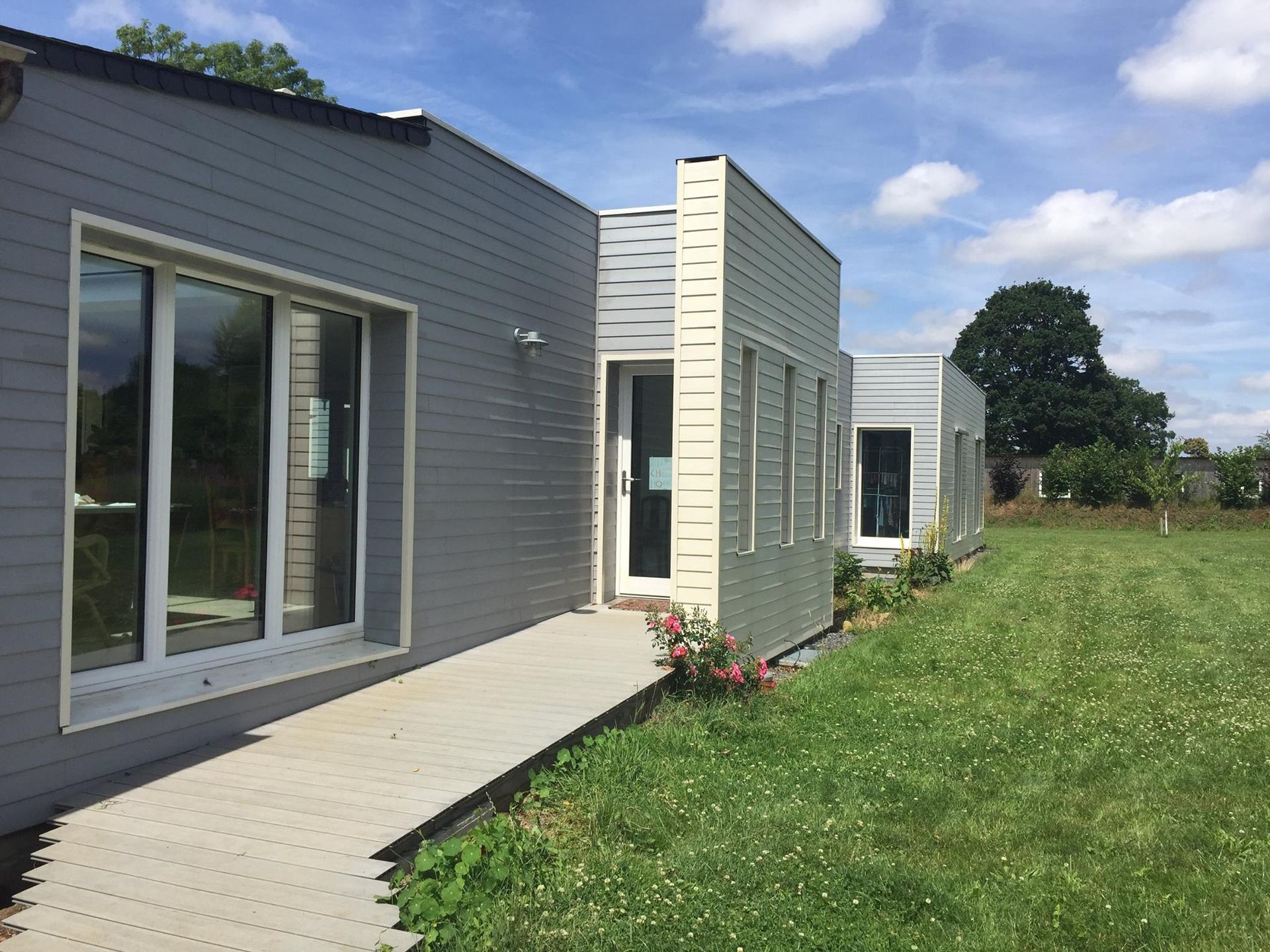 Baie vitrée et porte d'entrée d'un bâtiment avec bardage gris clair