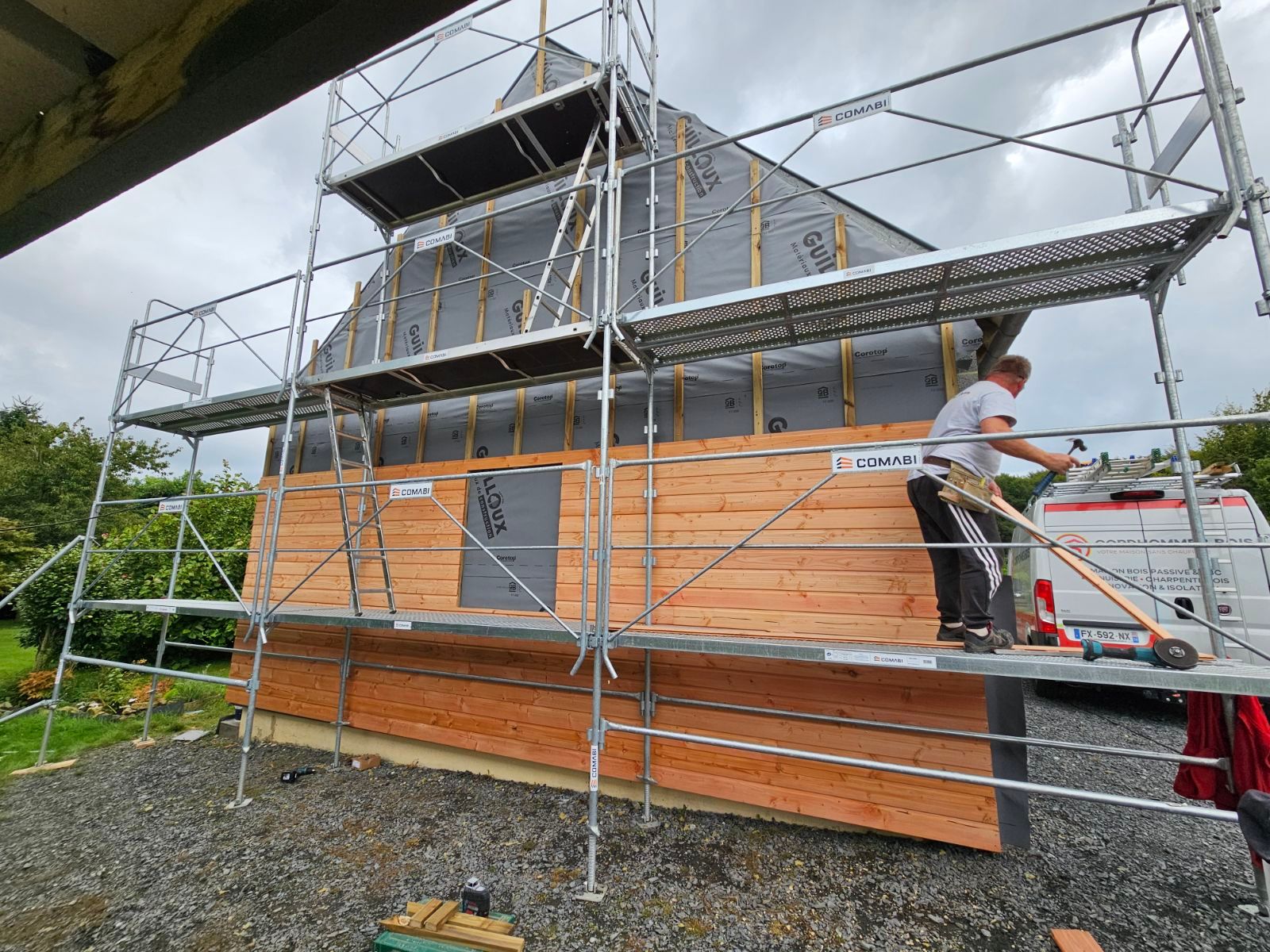 Échafaudage devant une maison dont le bardage est en train d'être posé
