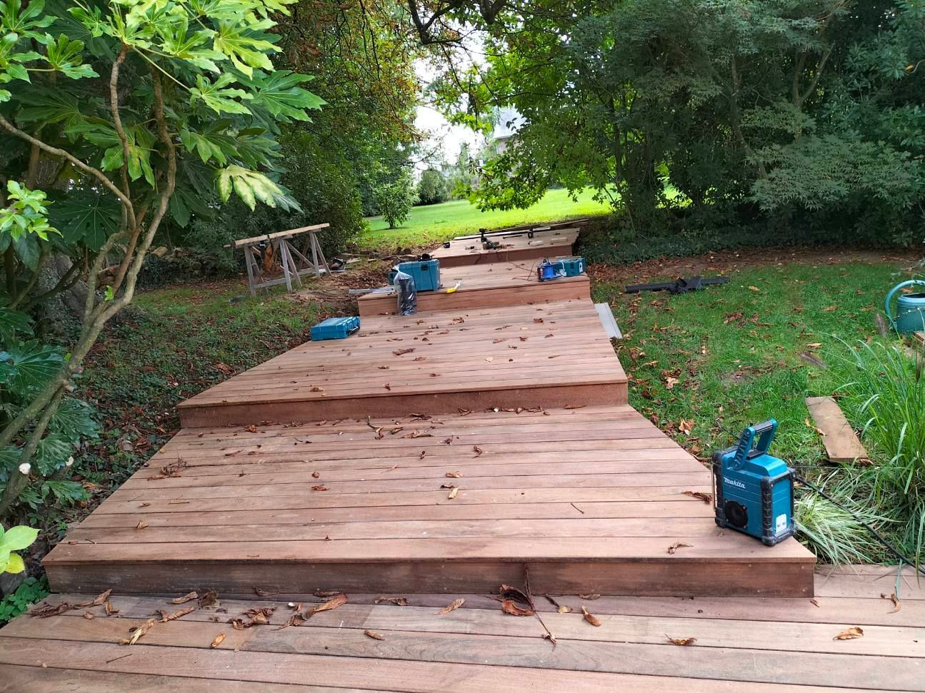 Passage entouré d'arbres via une terrasse en bois en escalier
