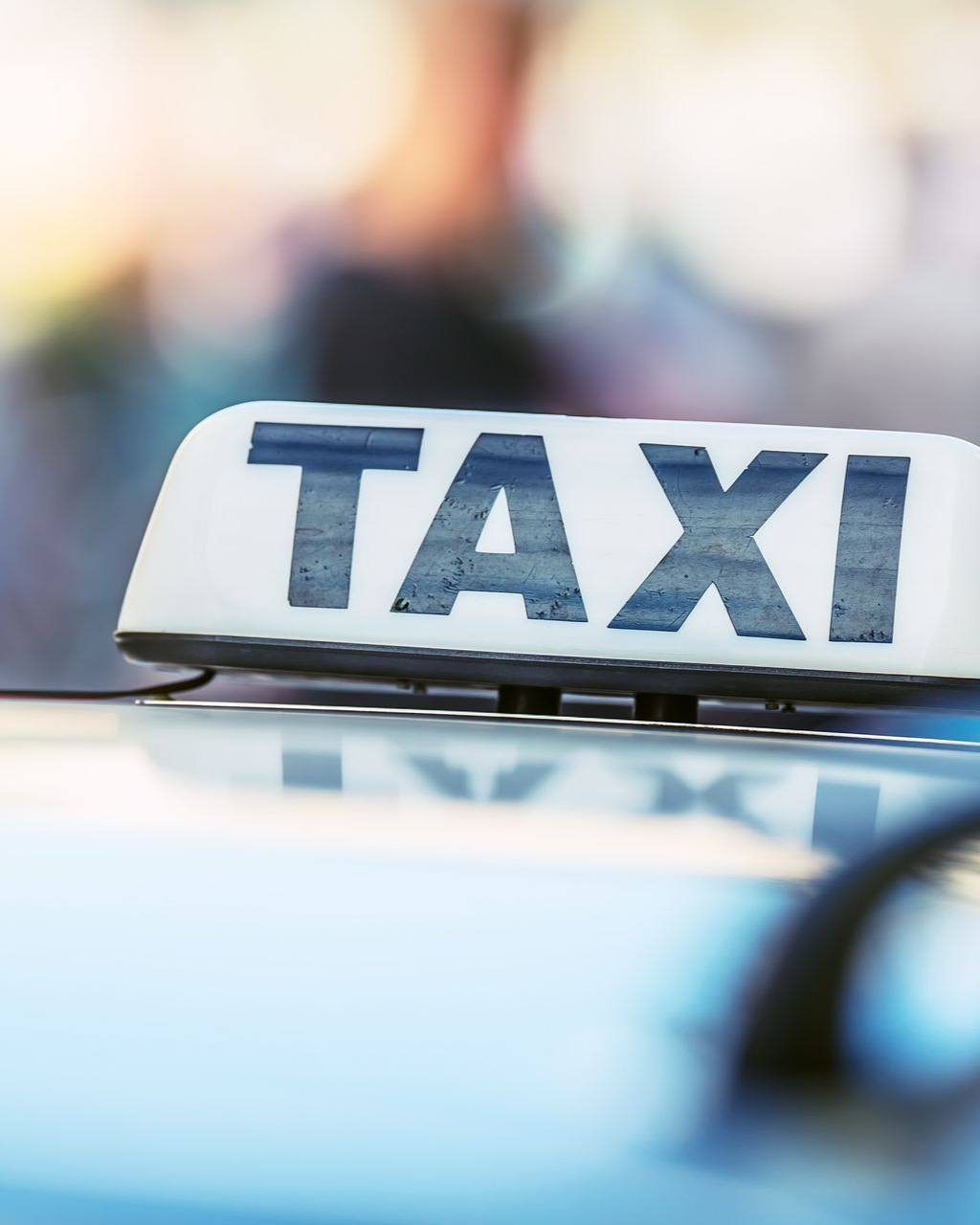 Panneau de toit de taxi avec l'inscription TAXI »en lettres bleues grasses. Panneau blanc, fond flou.