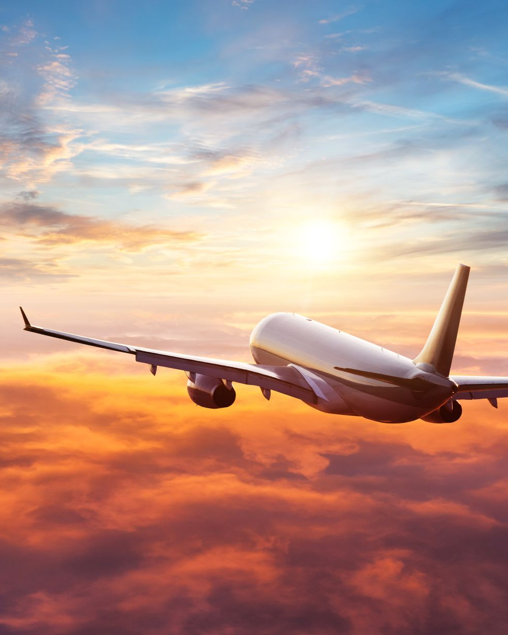 Avion volant à travers des nuages de coucher de soleil orangés et bleus.