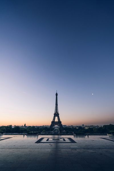 La tour Eiffel se détachant sur un ciel crépusculaire, avec un soupçon de lune.