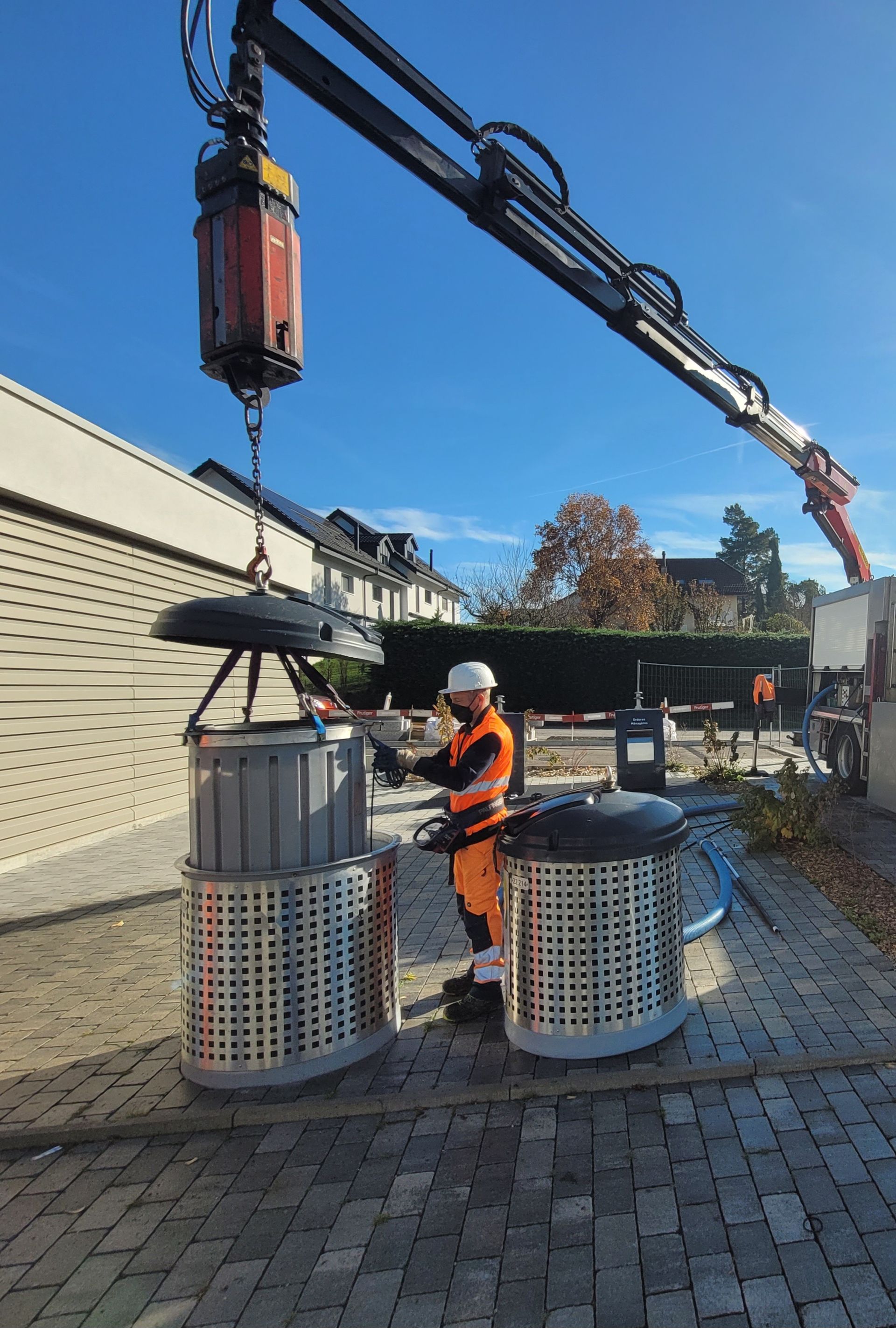 Un camion de recyclage à côté de plusieurs bacs de recyclage argentés sur une plate-forme, sous un ciel bleu.