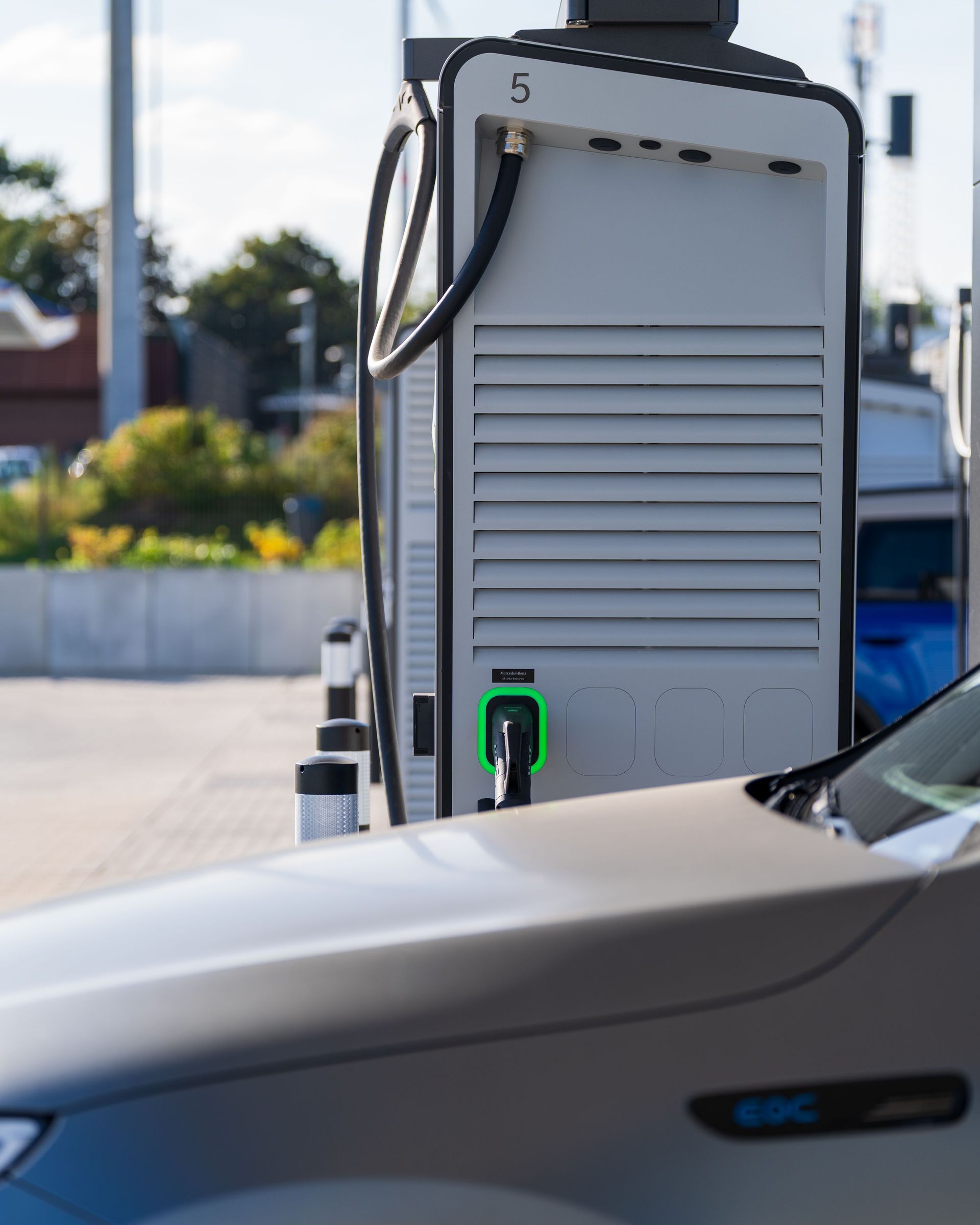 Borne de recharge pour véhicules électriques à côté d'une voiture argentée sur un parking