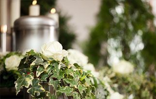 Hay una urna con flores y velas al fondo.