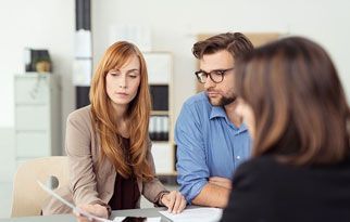 Un hombre y una mujer están sentados en una mesa hablando con una mujer.