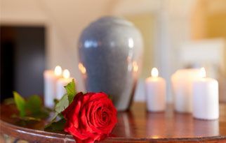 Una rosa roja está sobre una mesa al lado de velas.