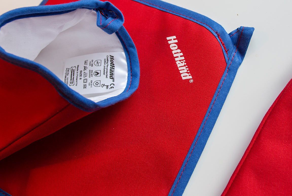 Punainen Helly Hansen -takki sinisillä reunuksilla ja valkoisella etiketillä, taitettu vaalealle pinnalle