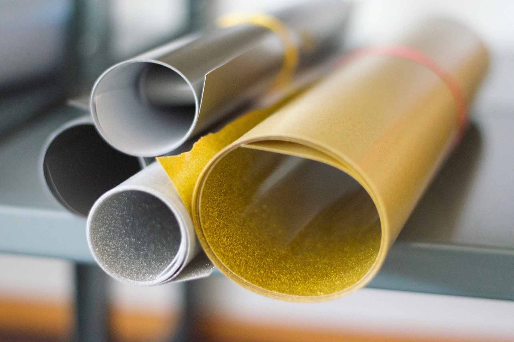 Lähikuva pinotuista metalli- ja keltaisista muoviputkista hyllyllä