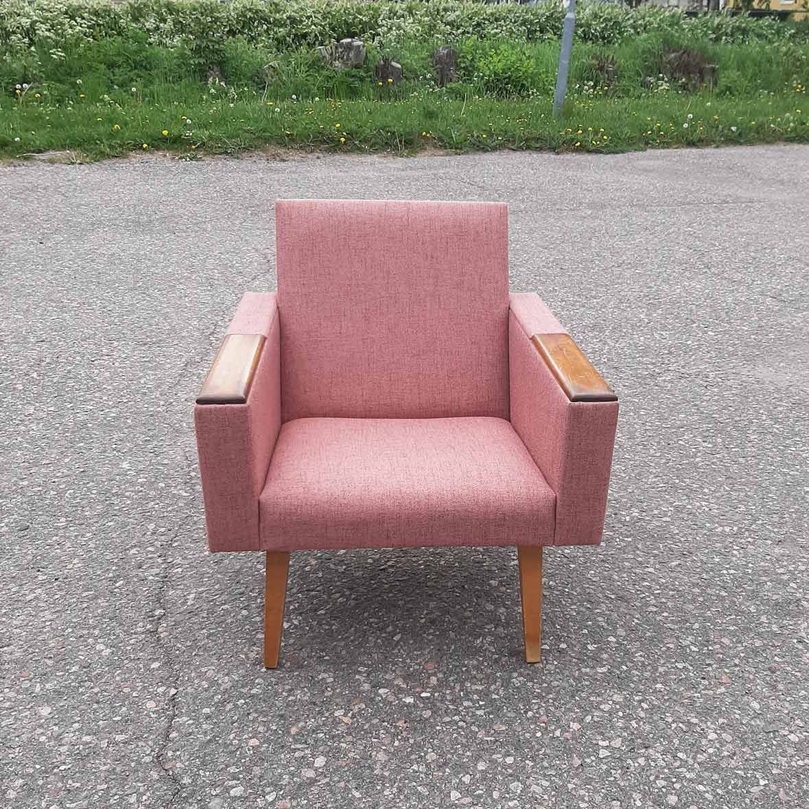 Vaaleanpunainen verhoiltu nojatuoli puisilla jaloilla laatoitettulla alustalla ulkona