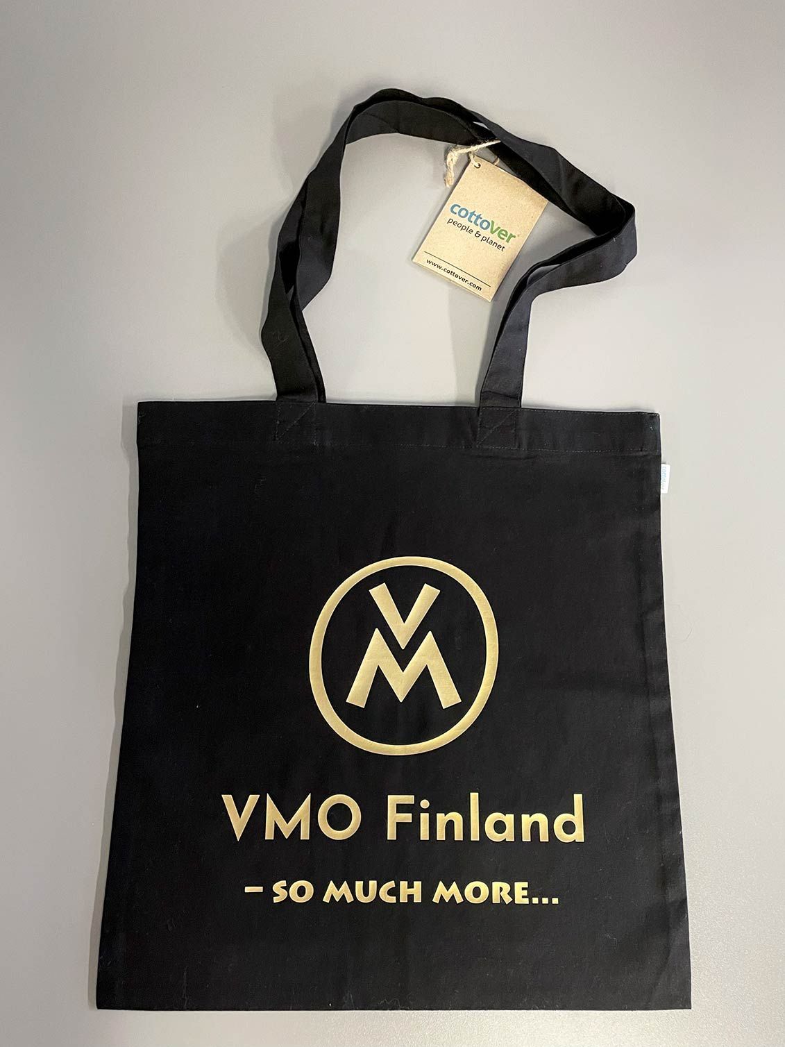 Musta VMO Finland -kassi, jossa on kultainen logo ja teksti vaalealla taustalla