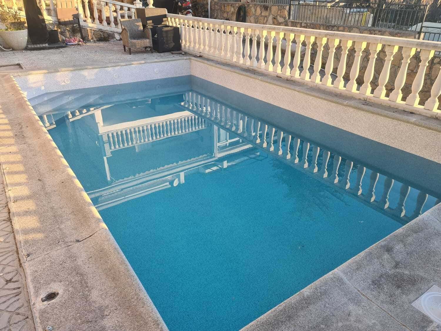 Piscina rectangular llena de agua azul, con una barandilla decorativa blanca a lo largo del lateral.