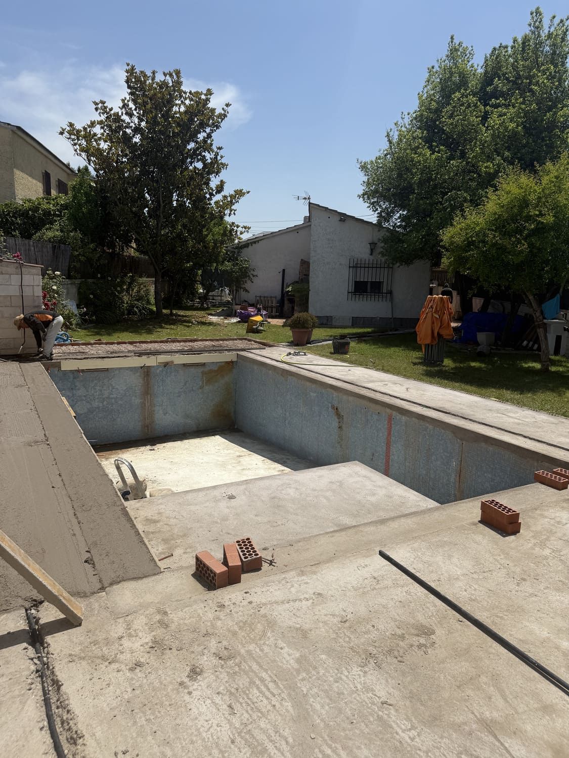 Piscina vacía en construcción en un día soleado. Ladrillos y hormigón visibles.