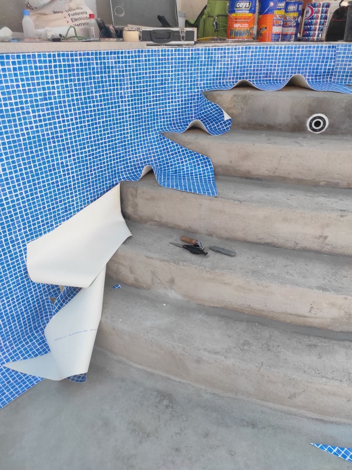 Piscina en construcción, se están instalando azulejos azules en los escalones.