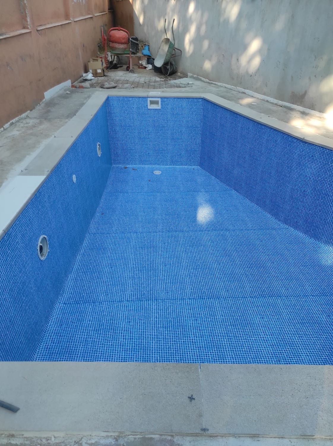 Piscina rectangular vacía revestida con mosaicos azules.