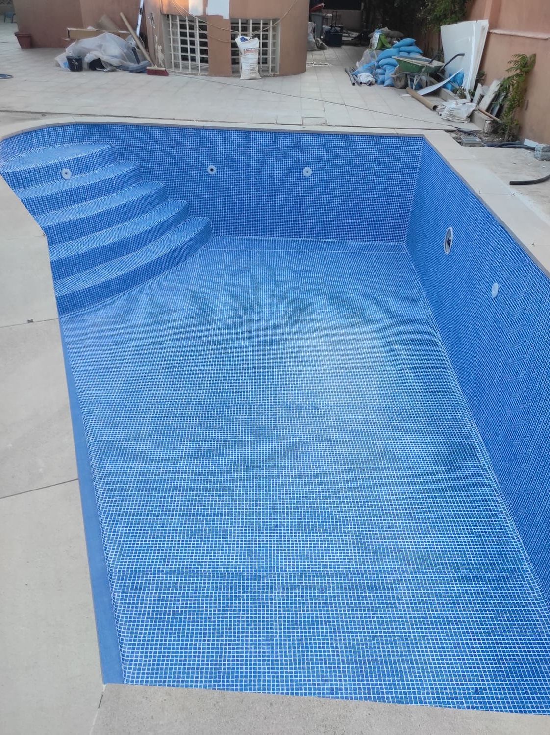 Piscina vacía revestida con mosaicos azules.