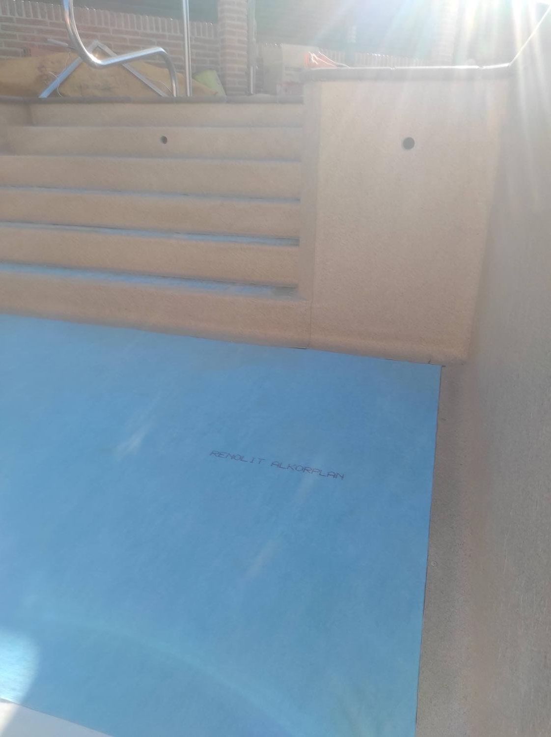 Esquina de una estructura en construcción. Aislamiento azul sobre una superficie clara con detalles de madera, en exteriores, soleado.