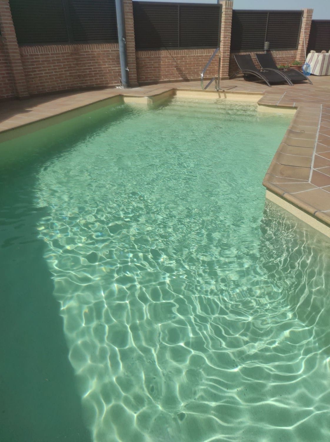 Piscina con agua clara, paredes de ladrillo y escaleras.