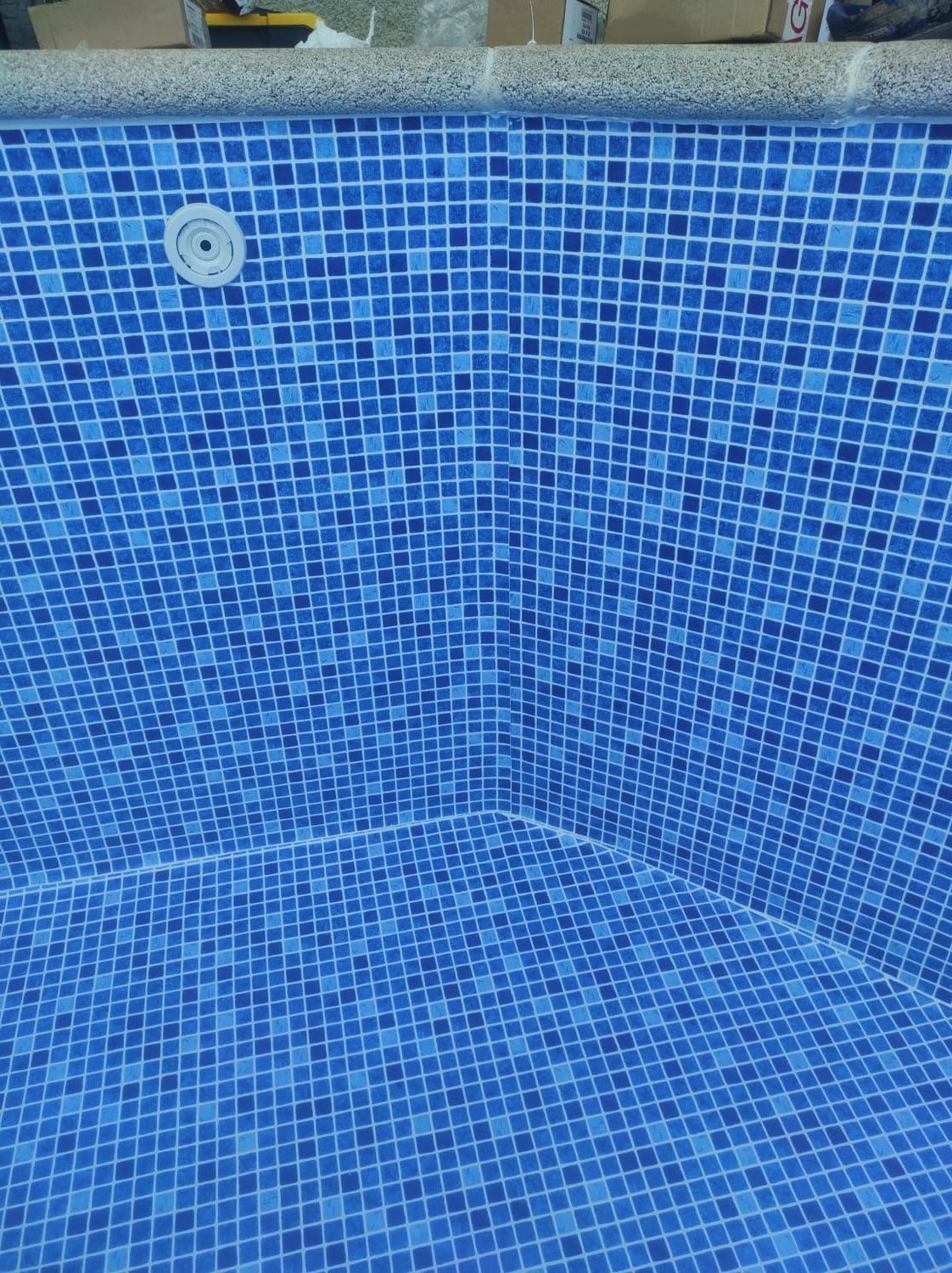 Interior de azulejos azules de una piscina con esquina y entrada de agua.