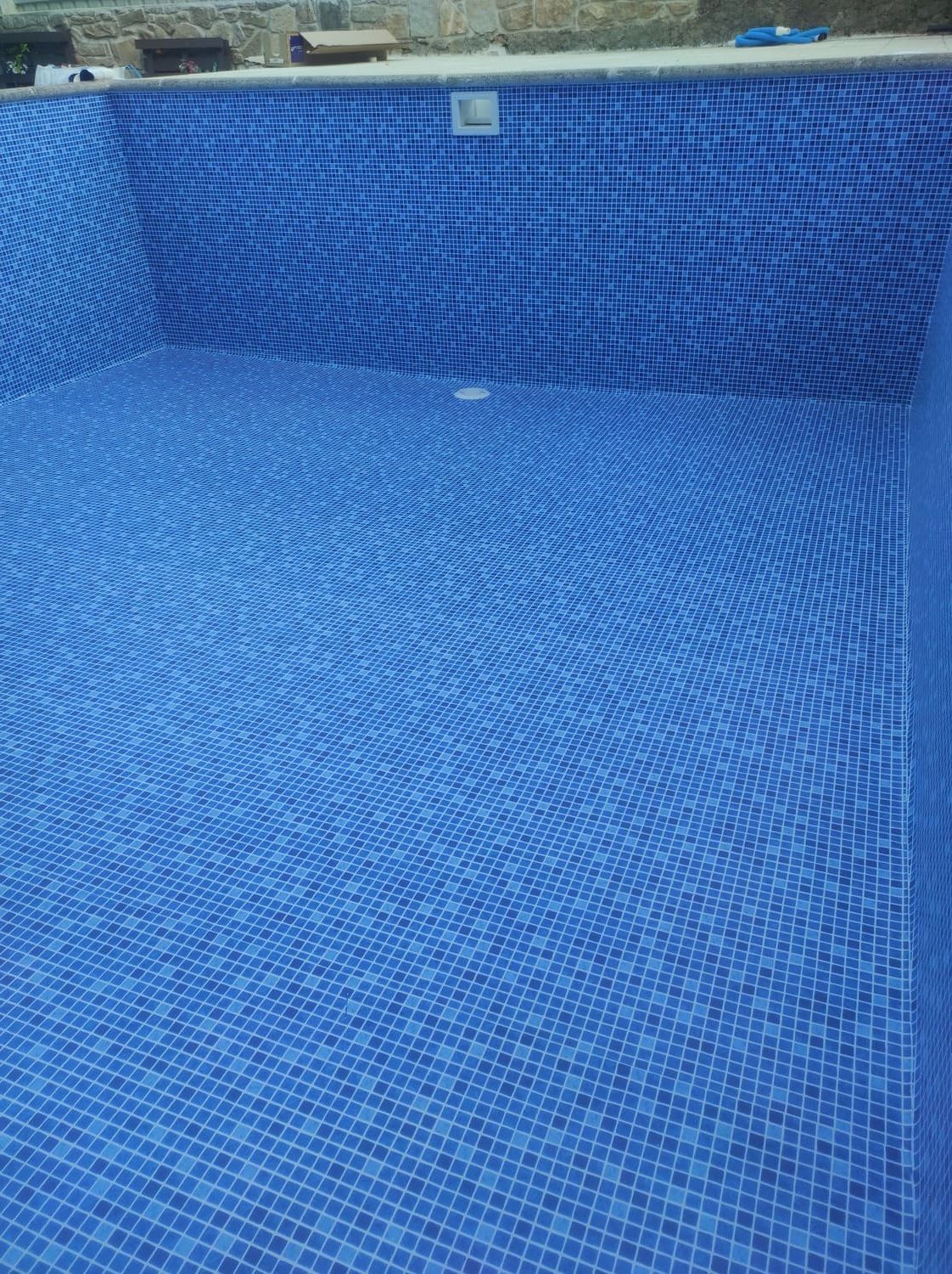 Piscina vacía revestida con mosaicos azules.