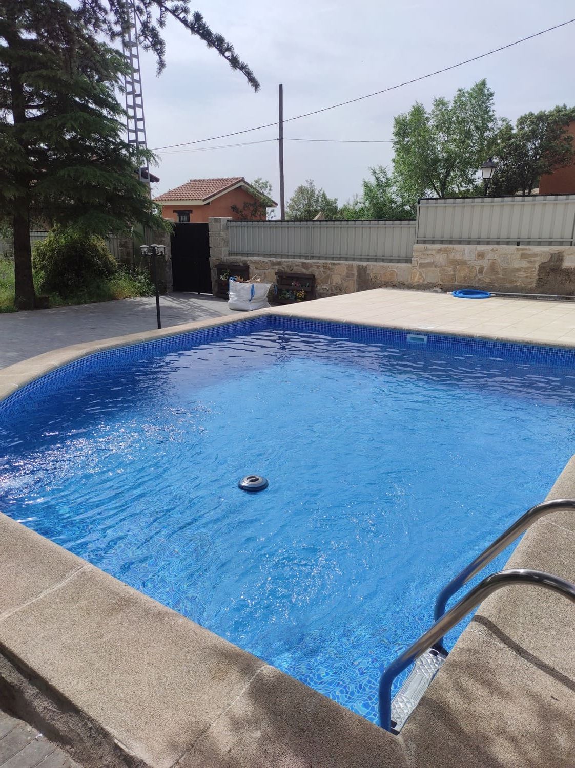 Piscina de agua azul y borde de piedra, al aire libre.