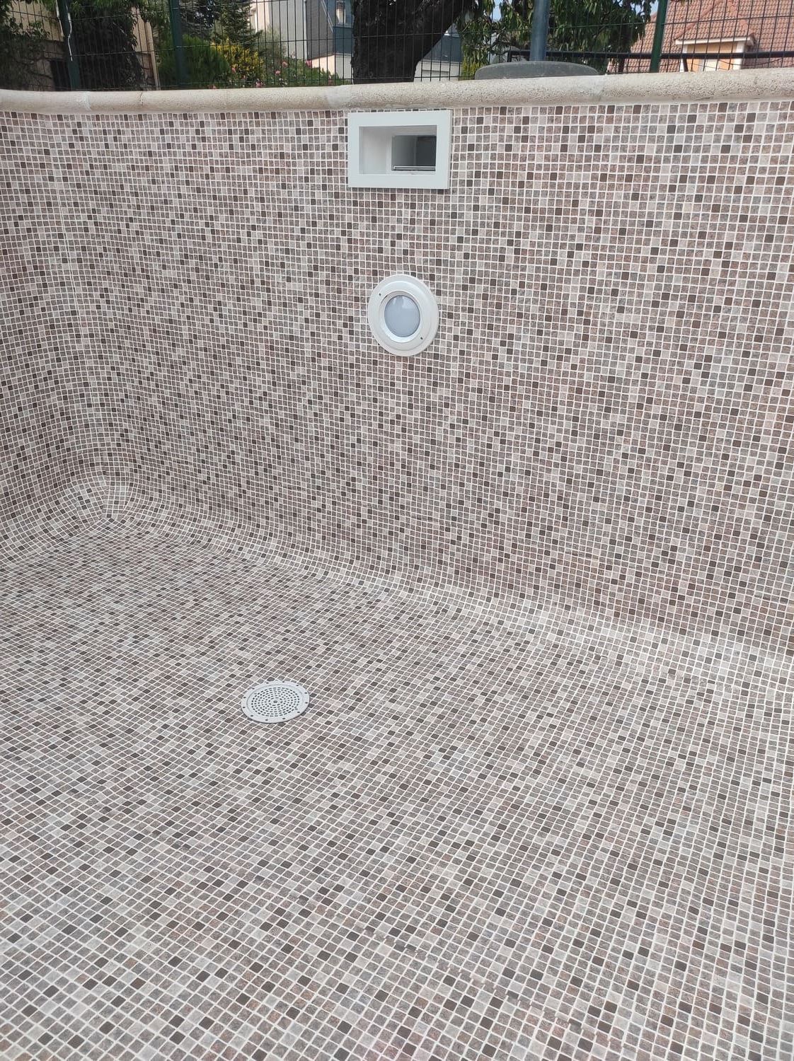 Interior de piscina vacía con mosaicos y accesorios.