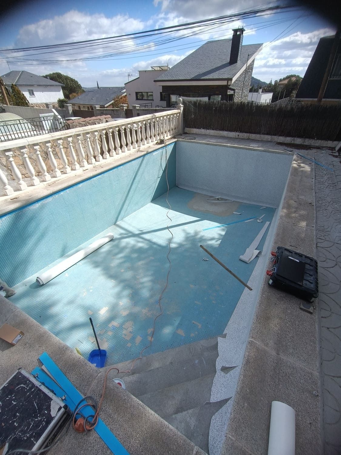 Piscina vacía con azulejos azules, en un entorno de patio trasero.