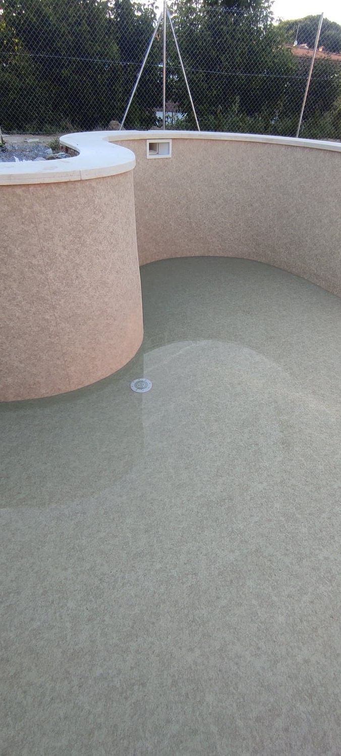 Una estructura circular de color beige con un interior lleno de una sustancia pálida y acuosa. Follaje verde al fondo.