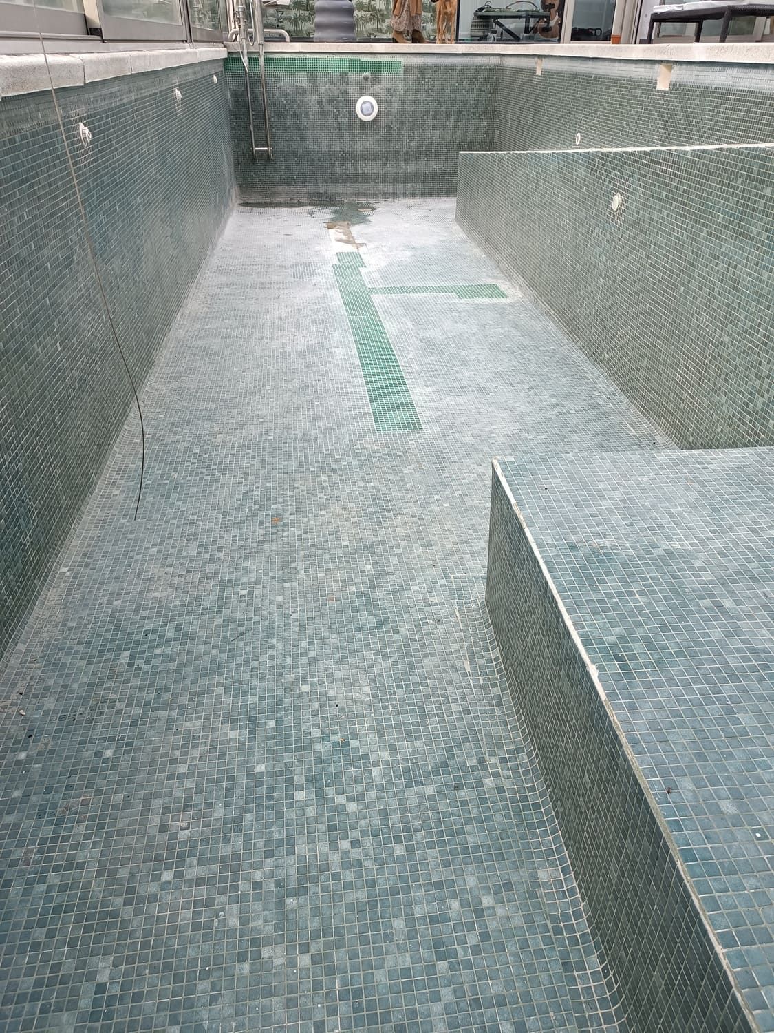 Piscina rectangular vacía con mosaicos de color turquesa.