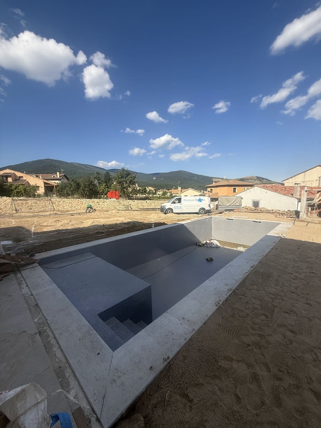 Piscina de hormigón en construcción al aire libre con fondo de montaña.