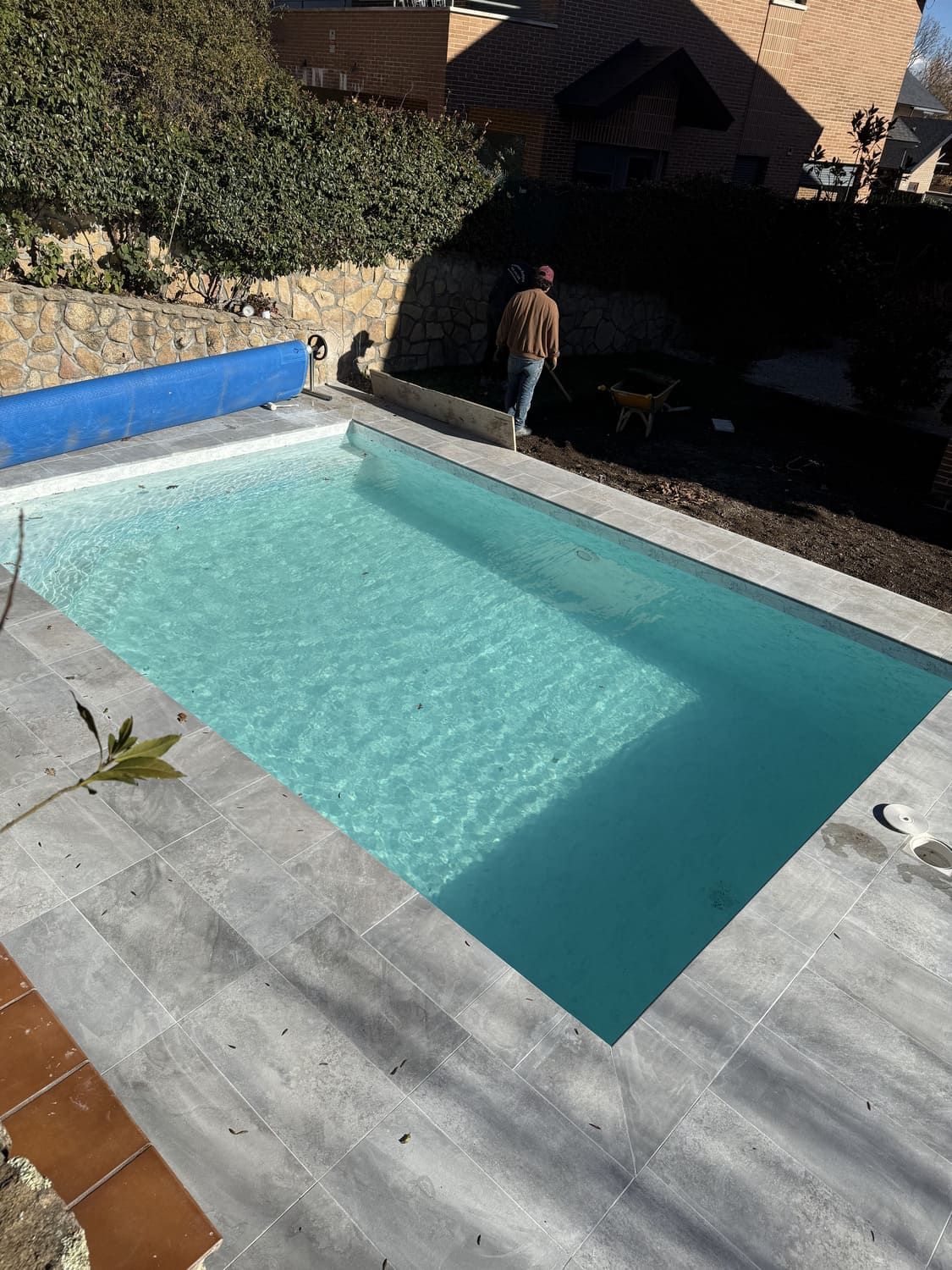 Piscina rectangular al aire libre con agua azul claro y una persona caminando cerca.