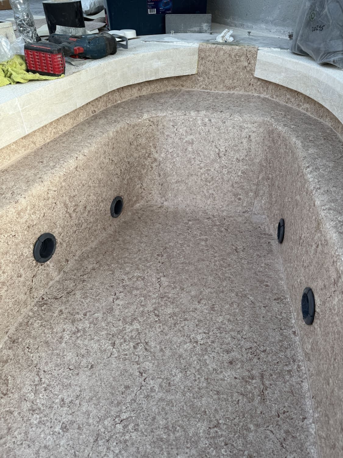 Un jacuzzi parcialmente construido con un interior moteado y chorros negros.