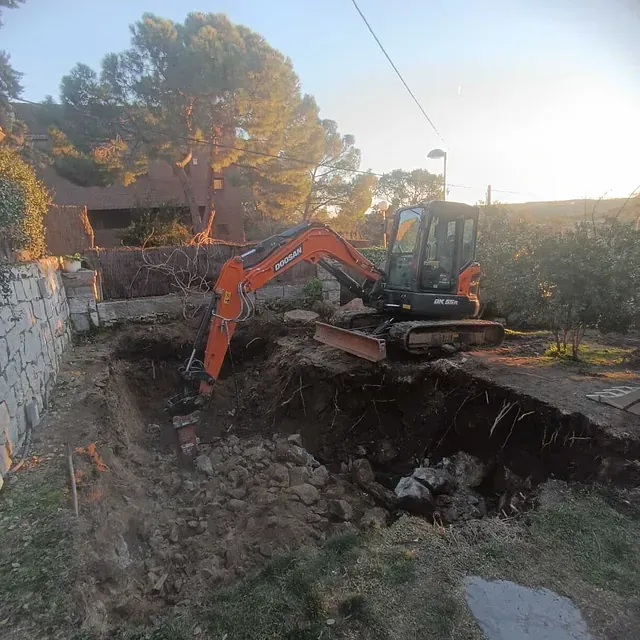 Una excavadora está cavando un hoyo en el suelo delante de una casa.