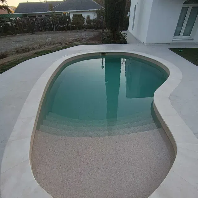 Una gran piscina con una casa al fondo.