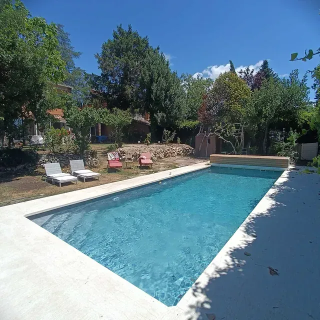 Una gran piscina rodeada de sillas y árboles.