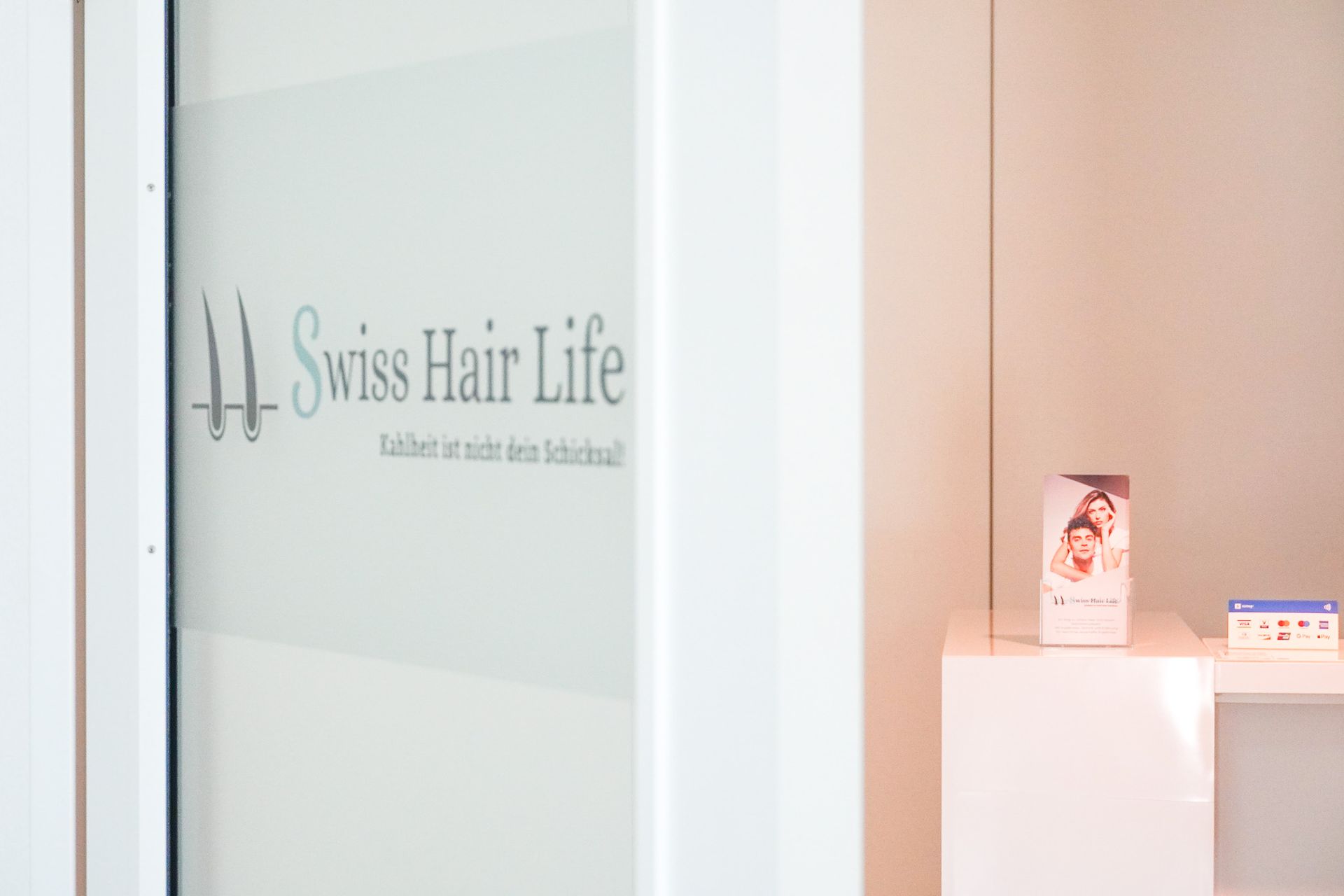 Eingang zu Swiss Hair Life mit Logo auf Milchglas.