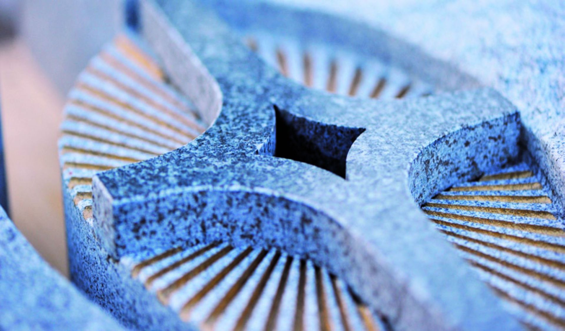 Nahaufnahme eines behauenen Steins mit sternförmigem Muster, strukturierter Oberfläche und blauen und beigen Farbtönen.