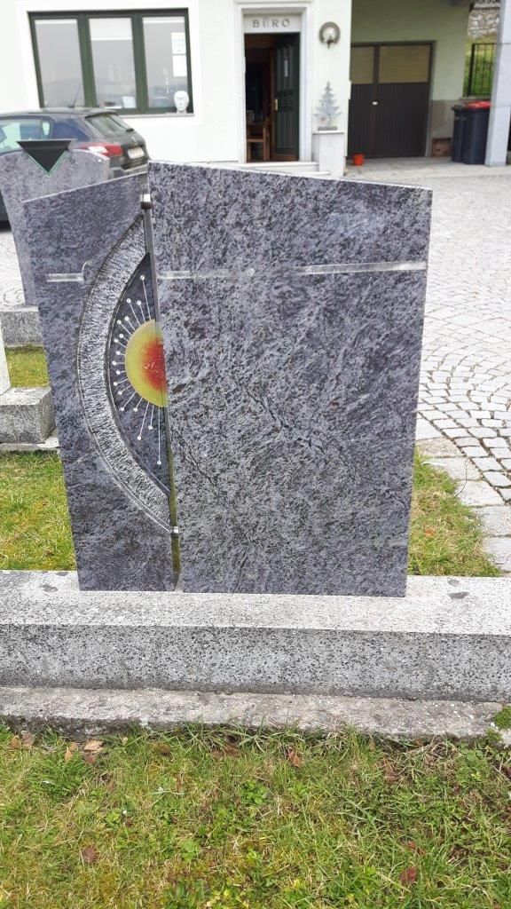 Granitgrabstein mit Mosaik-Sonnenmotiv.