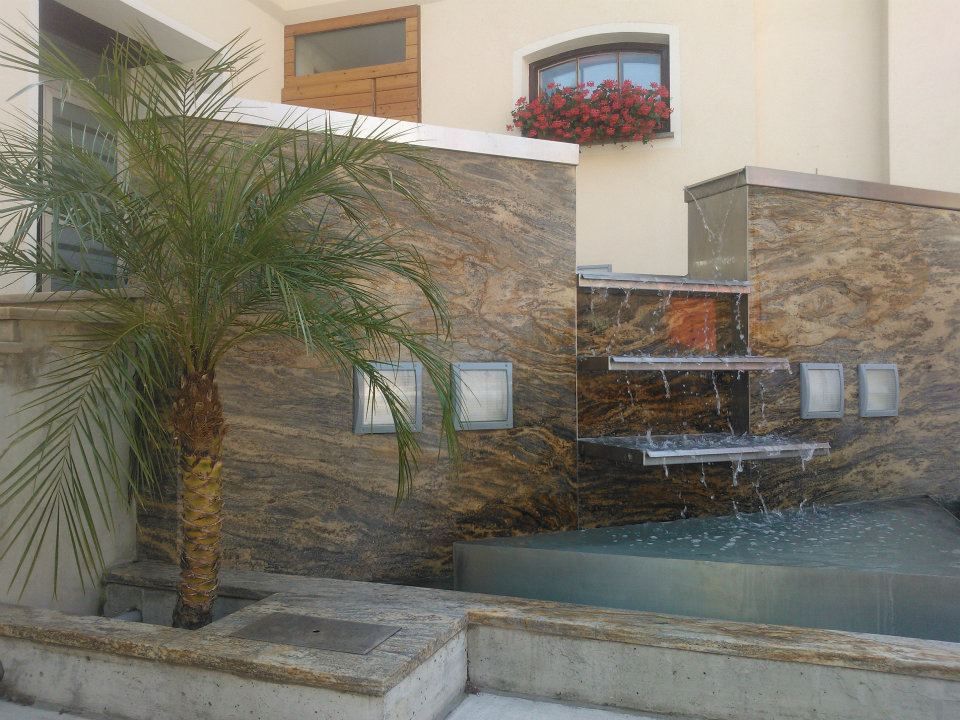 Palme neben einem mehrstufigen Wasserfall mit Granitwänden und einem Wasserbecken.