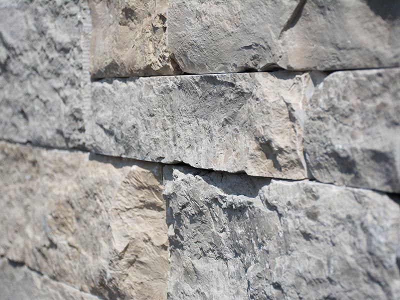 Nahaufnahme einer gestapelten Steinmauer in Grau- und Beigetönen.