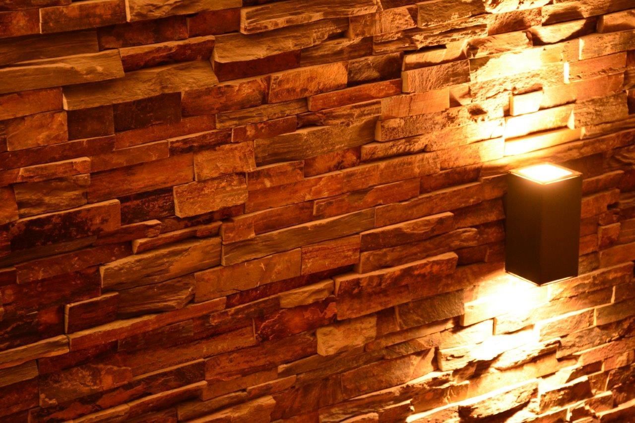 Backsteinwand mit warmer Beleuchtung und einer modernen Wandleuchte.