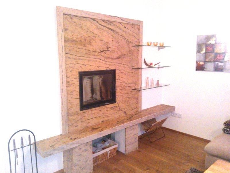 Kamin mit großer Granitumrandung und Glasregalen auf einem Hartholzboden, mit Dekorationselementen.