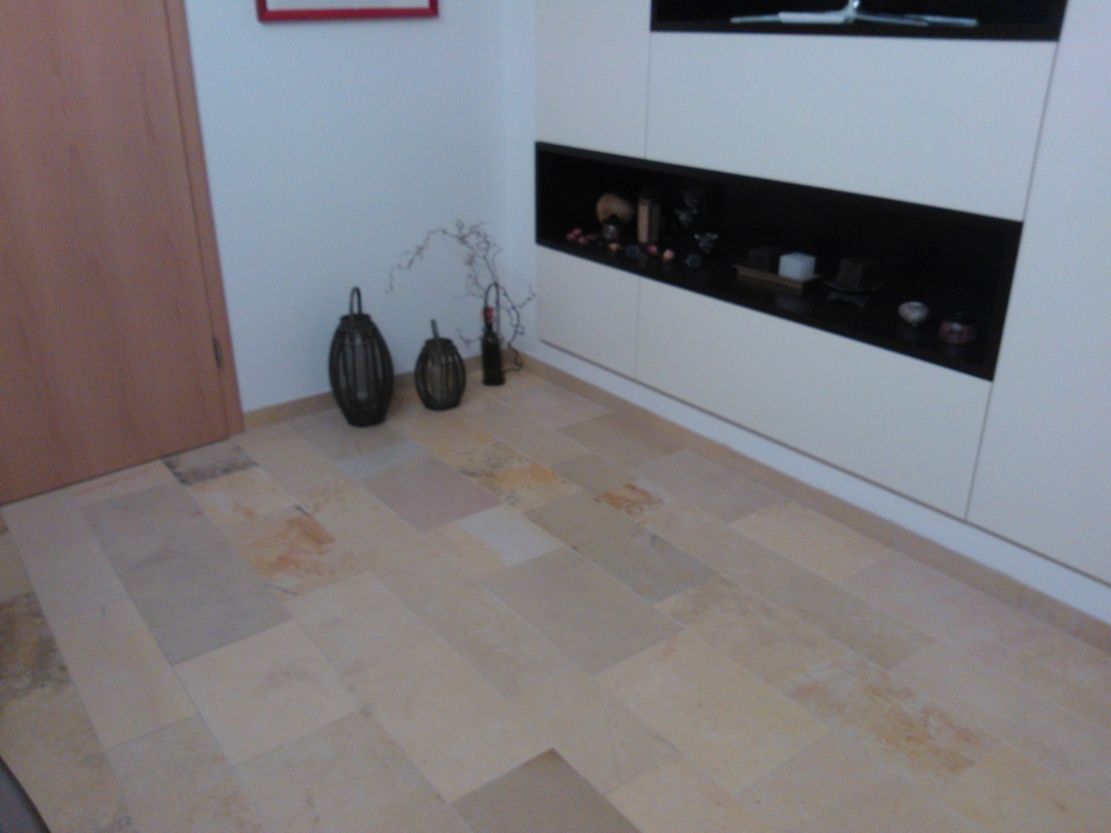 Steinboden in einem Zimmer mit geschlossener Holztür, weißem Schrank und dekorativen Vasen.