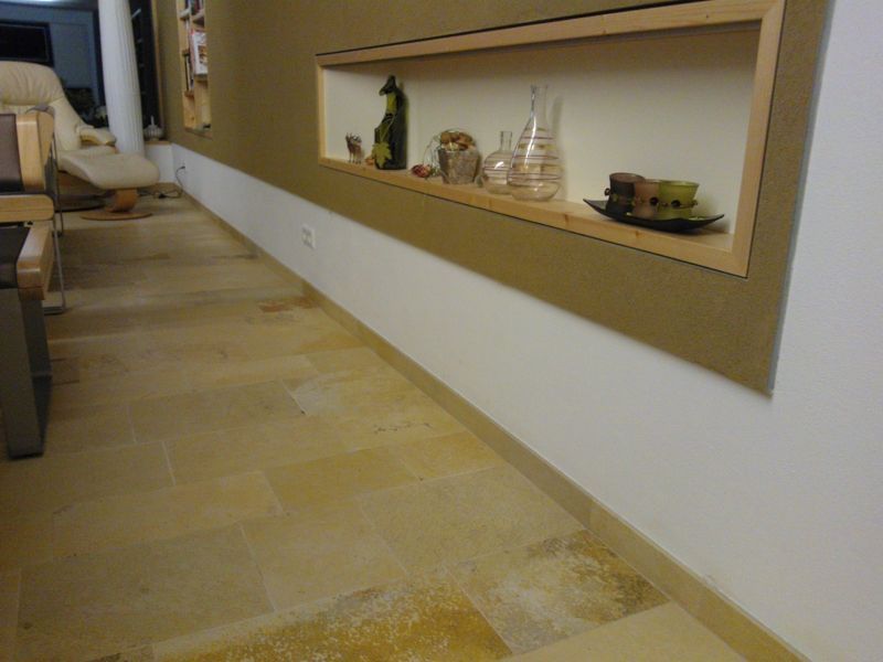 Ein langer Raum mit hellen Fliesenböden, einem eingelassenen Regal voller Dekorationsgegenstände und beigen und weißen Wänden.