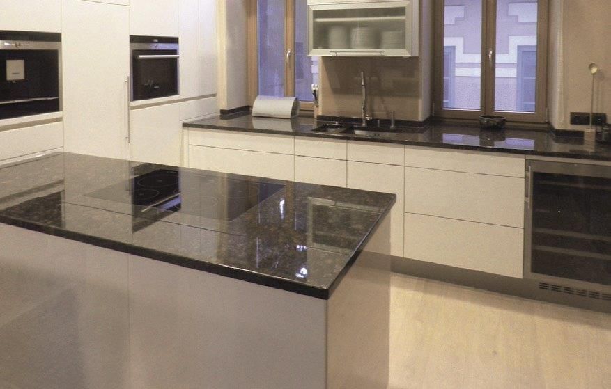 Moderne weiße Küche mit schwarzen Granitarbeitsplatten und Kochinsel.