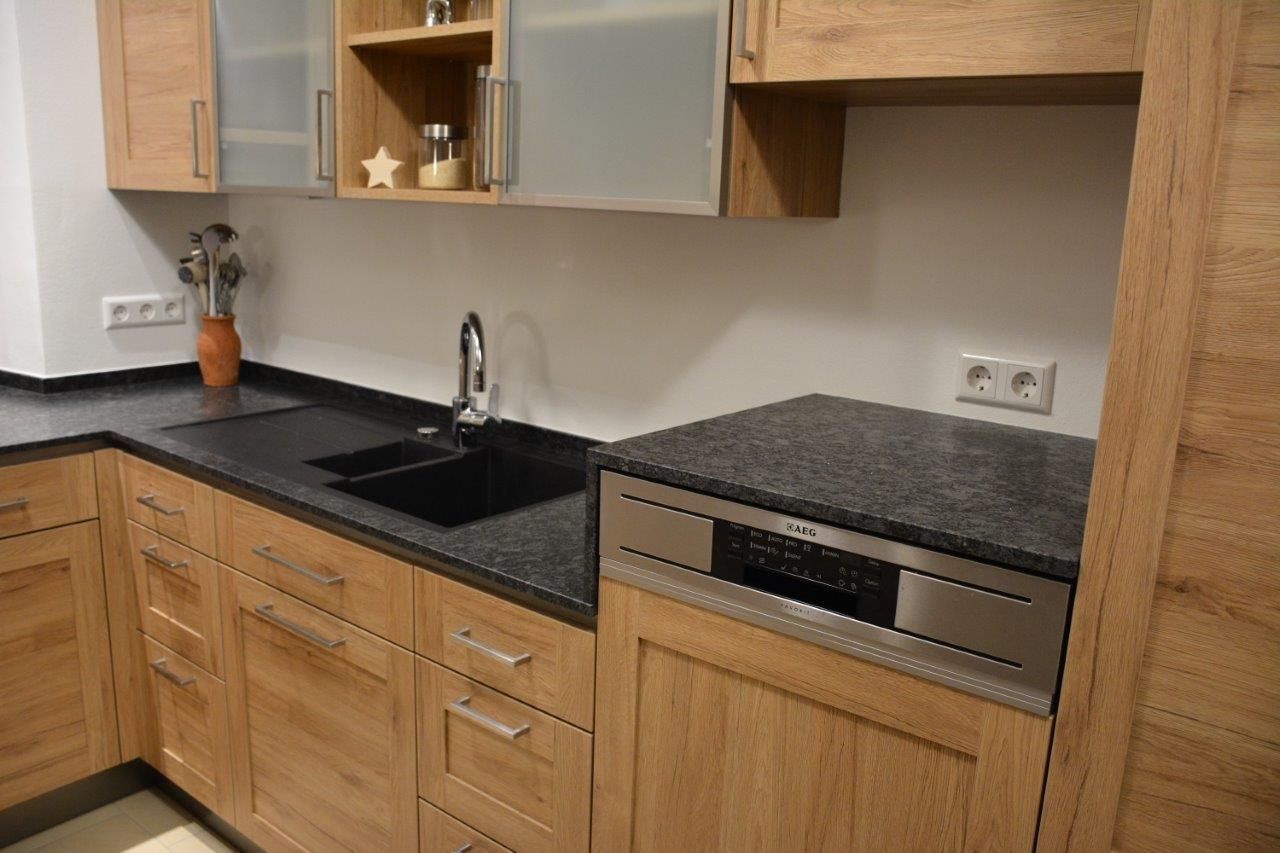 Eichenküche mit schwarzen Arbeitsplatten, Spüle, Geschirrspüler und Oberschränken.