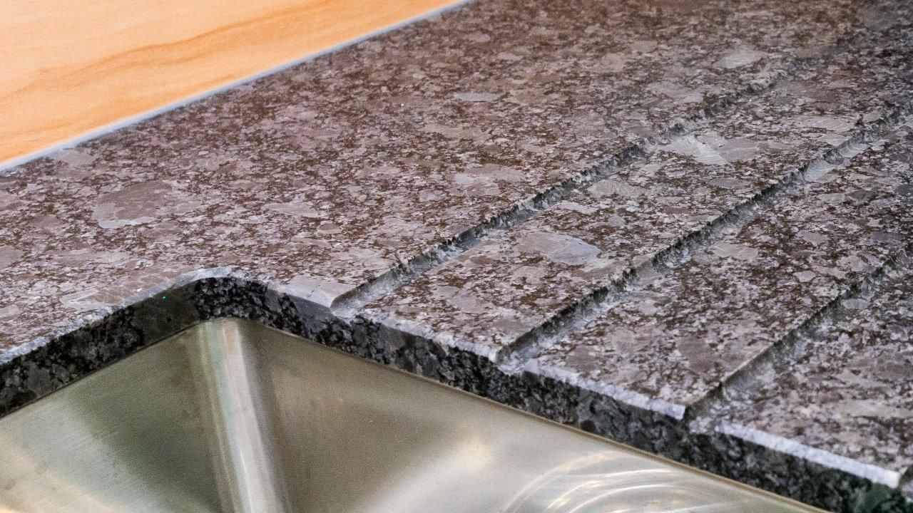 Granit-Arbeitsplatte mit integriertem Spülbecken und Abtropfrillen.