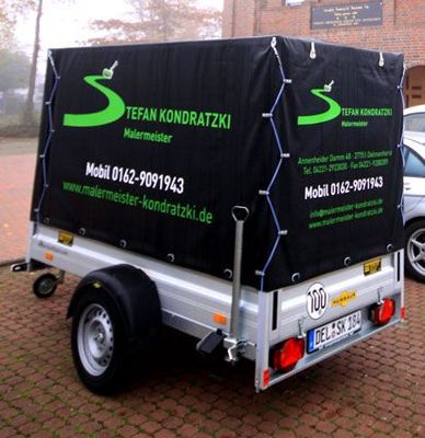 Ein Anhänger mit einer schwarzen Plane, auf der Stefan Kondratzki steht