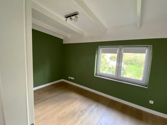 Ein leerer Raum mit grünen Wänden und einem Fenster