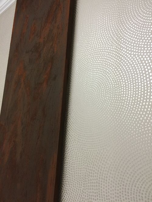 Neben einer Wand steht ein Holzregal mit einem Muster darauf.